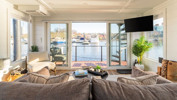 Een woonkamer met uitzicht op een jachthaven, een bank, een stoel, een televisie en een plant.