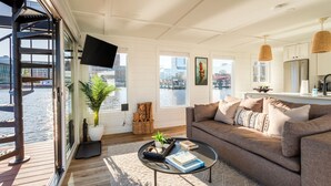 Een moderne woonkamer met een bank, salontafel en grote ramen met uitzicht op een stadsgezicht.