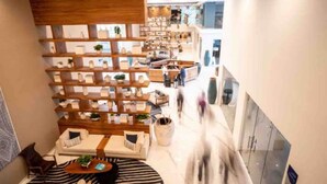 Un interior modern amb una zona d'estar central, mobles d'emmagatzematge de fusta i una escala que condueix a un nivell superior.