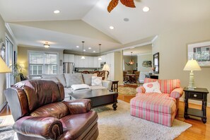 A spacious living room with a leather sofa, a striped armchair, and a dining area in the background.