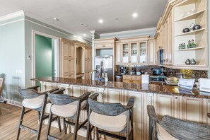 A spacious kitchen with a large island, bar stools, and modern appliances.