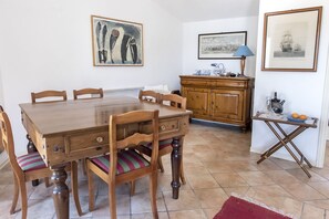 Un coin repas avec une table et des chaises en bois, un buffet en bois et une petite table pliante avec une lampe et des oranges.