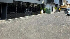 A modern building with a wooden sloped roof, large glass windows, and a paved driveway. - Westine Hotels and Spa (Lekki)