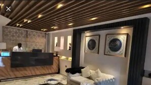 A modern hotel lobby with a reception desk, seating area, and decorative wall art. - Westine Hotels and Spa (Lekki)
