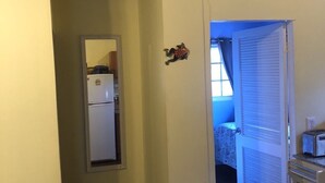 A narrow hallway with a refrigerator, a small decorative frog, and a door leading to a room with a window and a toaster. - Starfish Villa, quiet Caribbean paradise with wonderful valley views (Cruz Bay)