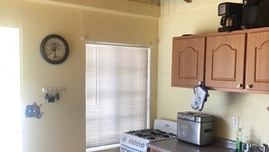 A kitchen with wooden cabinets, a stove, a toaster, and a window with blinds. - Starfish Villa, quiet Caribbean paradise with wonderful valley views (Cruz Bay)