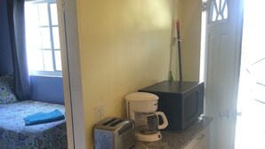 A compact room with a bed, a kitchenette, and a door leading to another room. - Starfish Villa, quiet Caribbean paradise with wonderful valley views (Cruz Bay)