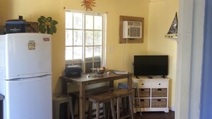 A kitchen with a wooden ceiling, a refrigerator, a table with chairs, a window, and a television. - Starfish Villa, quiet Caribbean paradise with wonderful valley views (Cruz Bay)