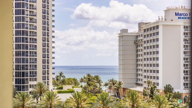 A high-rise hotel with a view of the ocean, palm trees, and a clear sky. - Ocean View, 1BD+1.5BA, Steps To Beach. Heated Pool. Ocean reserve (Sunny Isles Beach)