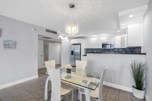 Une cuisine moderne dotée d’un îlot central, de meubles blancs et d’un réfrigérateur en acier inoxydable.