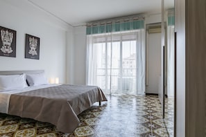 Ein Hotelzimmer mit Bett, Fenster mit Vorhängen und einem gemusterten Boden.