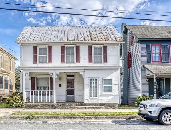 A two-story white house with red shutters, a front porch, and a garage. - 1880's Historic Beach House... Easy Walk to the Beach, Shopping & Restaurants (Lewes)