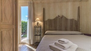 Une chambre à coucher avec un lit, une table de chevet, une lampe et une vue sur l’extérieur.