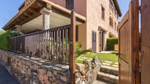 Un mur de pierre, une porte en bois et un bâtiment doté d’un balcon.