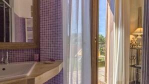 Une salle de bain avec un lavabo, un miroir et une vue sur un jardin, visible à travers une porte vitrée.