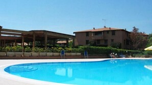 Une piscine dotée d’une zone couverte, un bâtiment à toit plat et un ciel dégagé.