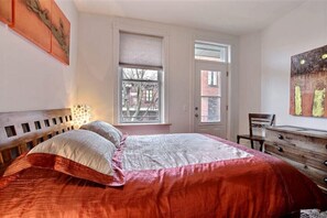 Un dormitorio con cama, cómoda y ventana con persianas.