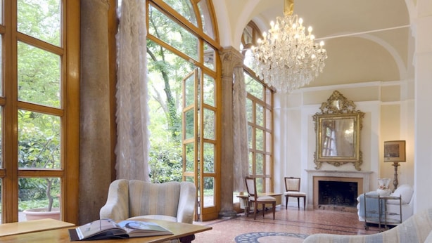 A spacious room with large windows, a chandelier, a fireplace, and a mirror on the wall. - GuestHost - Stunning villa divided over three levels (ground, first and second), WITHOUT lift. There are internal stairs to access the upper floors.In 410 square meters of space it comfortably accommodates 12 people.Detached villa with a private garden s (Ferrara)