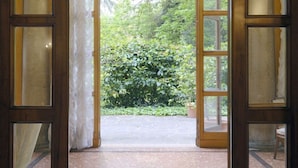 An open wooden door leading to a garden with a potted plant and a chair. - GuestHost - Stunning villa divided over three levels (ground, first and second), WITHOUT lift. There are internal stairs to access the upper floors.In 410 square meters of space it comfortably accommodates 12 people.Detached villa with a private garden s (Ferrara)
