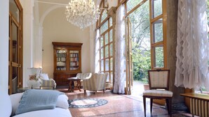 A spacious room with a large window, a chandelier, a wooden bookcase, and a round table. - GuestHost - Stunning villa divided over three levels (ground, first and second), WITHOUT lift. There are internal stairs to access the upper floors.In 410 square meters of space it comfortably accommodates 12 people.Detached villa with a private garden s (Ferrara)