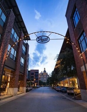 A street view with a building featuring a 'Pearl' sign, brick facades, and a clear sky.