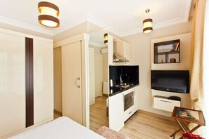 Habitació d'hotel moderna amb una cuineta, televisió de pantalla plana i un llit.