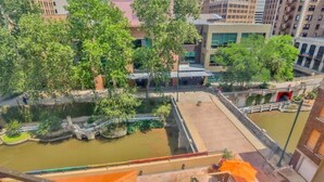 A courtyard with a water feature, trees, and a bridge. - Walk Everywhere - Charming Studio on the Riverwalk (San Antonio)