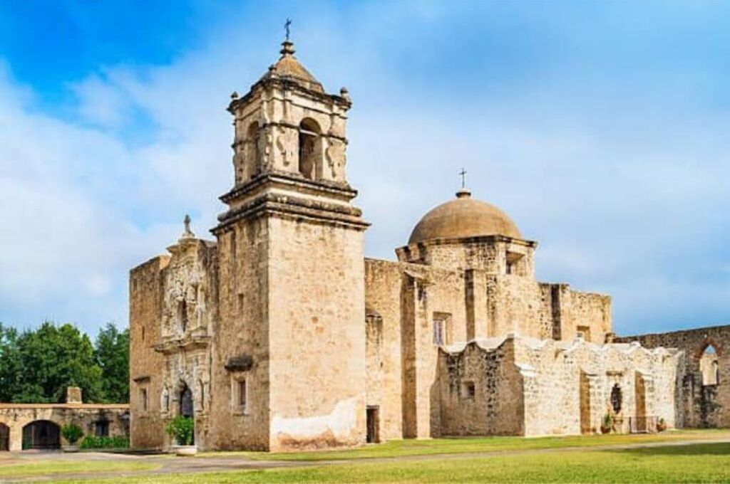 A historic building with a bell tower and a dome, featuring arched windows and a courtyard.