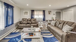 Un salon spacieux avec un canapé en cuir marron, une table basse blanche et un tapis à motifs bleus.