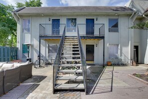 Ein zweistöckiges Haus mit einer zentralen Treppe, einem überdachten Außenbereich zum Sitzen und einem draußen abgestellten Fahrrad.