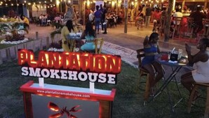 Area esterna con tavoli e un cartello per Plantation Smokehouse.