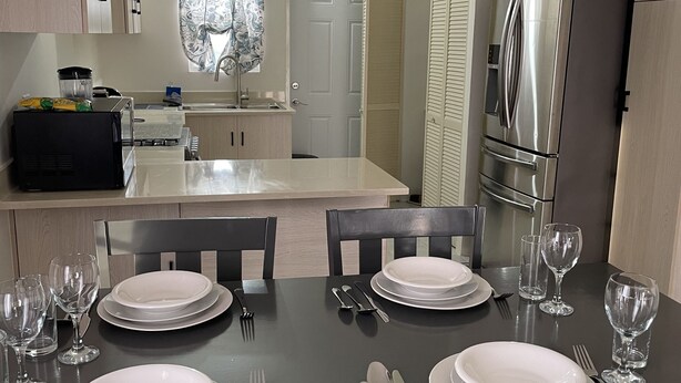 Una cucina moderna con zona pranzo apparecchiata per quattro persone.