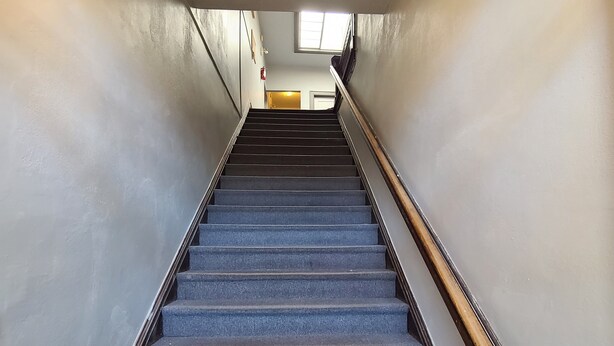 Un escalier muni d’une rampe et d’un luminaire fixé au mur.