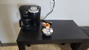 Une machine à café Keurig noire est posée sur une table noire, et son cordon d’alimentation est branché.