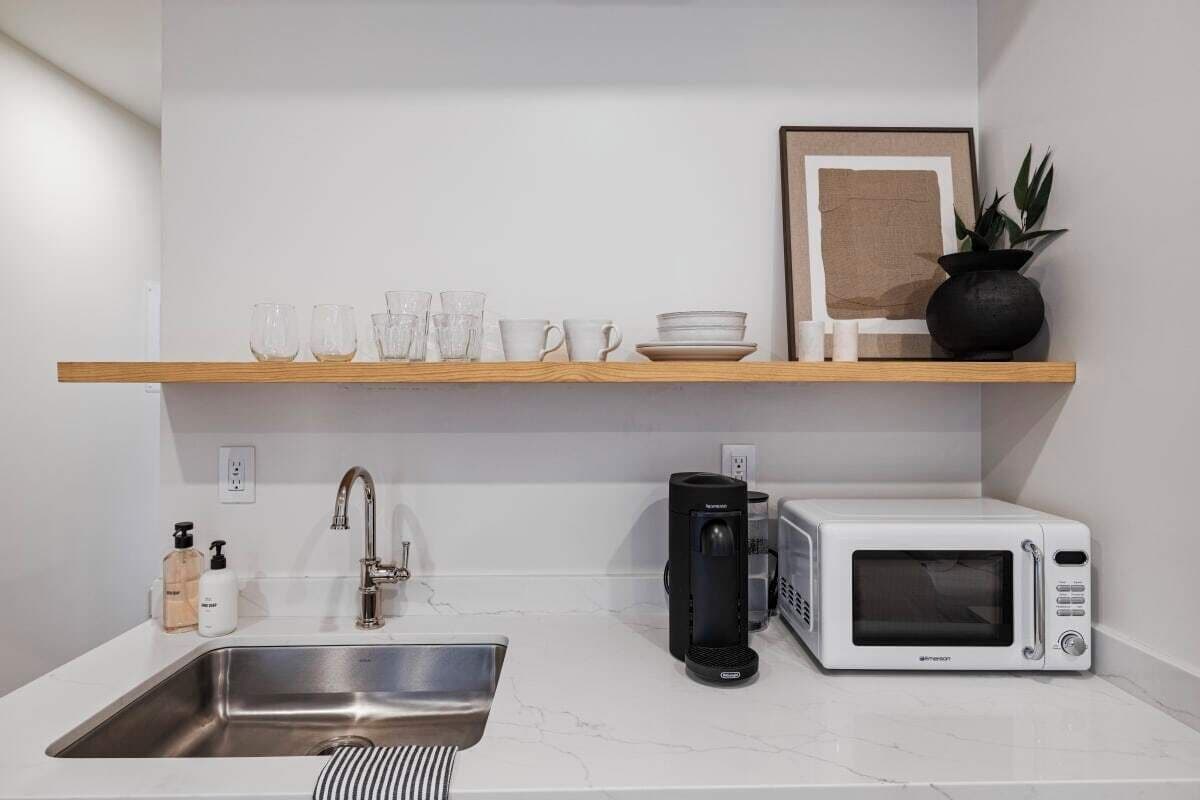 Une cuisine moderne équipée d’un évier en acier inoxydable, d’un four à micro-ondes blanc et d’une machine à café.