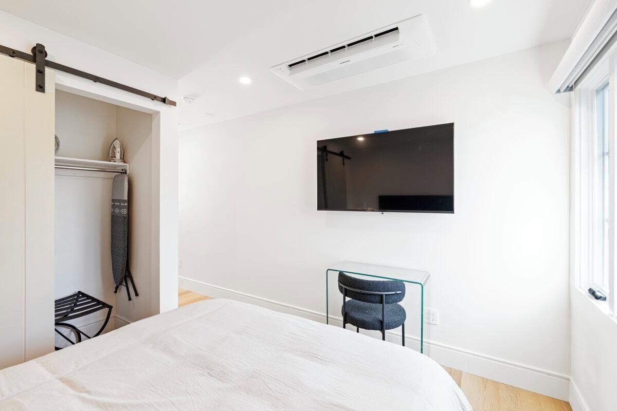 Une chambre moderne avec un lit, un bureau et un téléviseur fixé au mur.