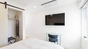 Une chambre moderne avec un lit, un bureau et un téléviseur fixé au mur.