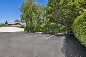 A parking lot with marked spaces, surrounded by dense greenery and a building in the background. - Casa Jardin, a ZenStay Hotel (Santa Barbara)