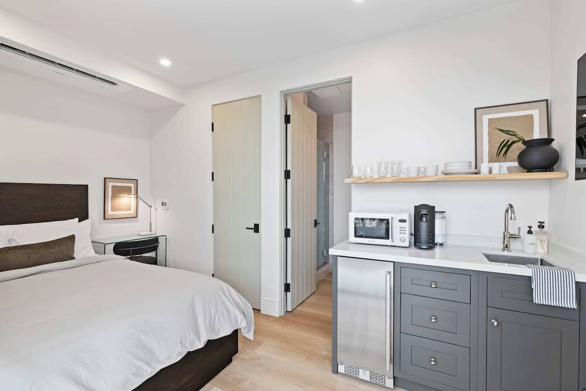 Cozy retreat with a neatly made bed, kitchenette, and wardrobe.