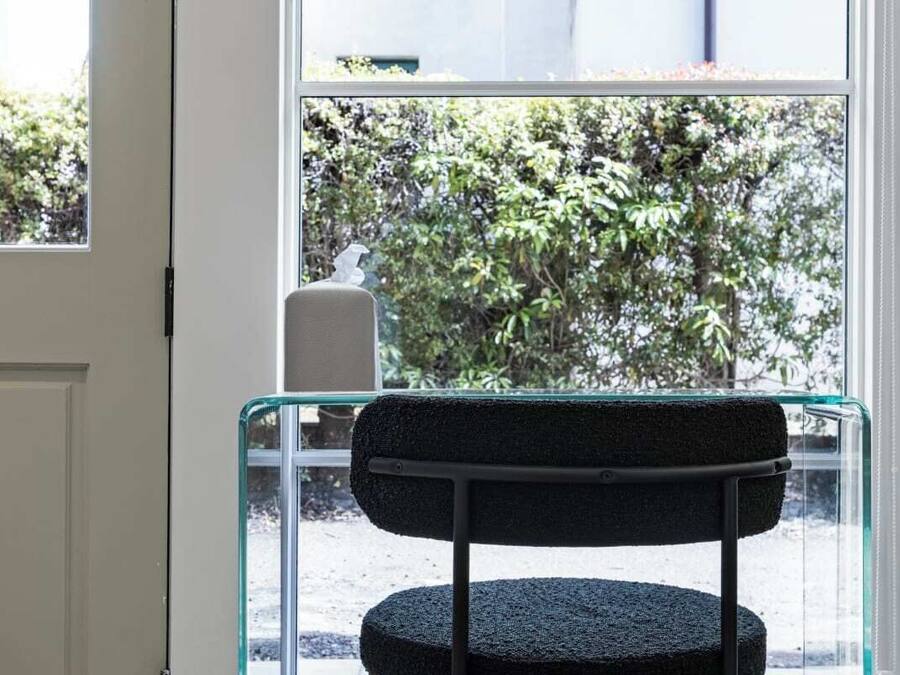 Ein Stuhl mit strukturiertem Sitz und Rückenlehne, vor einem Fenster mit Blick auf grüne Landschaft.