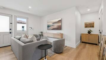 Un salon moderne avec un canapé gris, une petite table ronde et un meuble en bois.