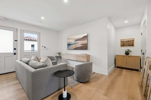 Uma sala de estar moderna com um sofá cinzento, uma mesinha redonda e um armário de madeira.