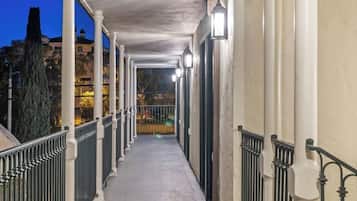 Un couloir couvert, doté d’une rambarde métallique, qui mène à une porte.
