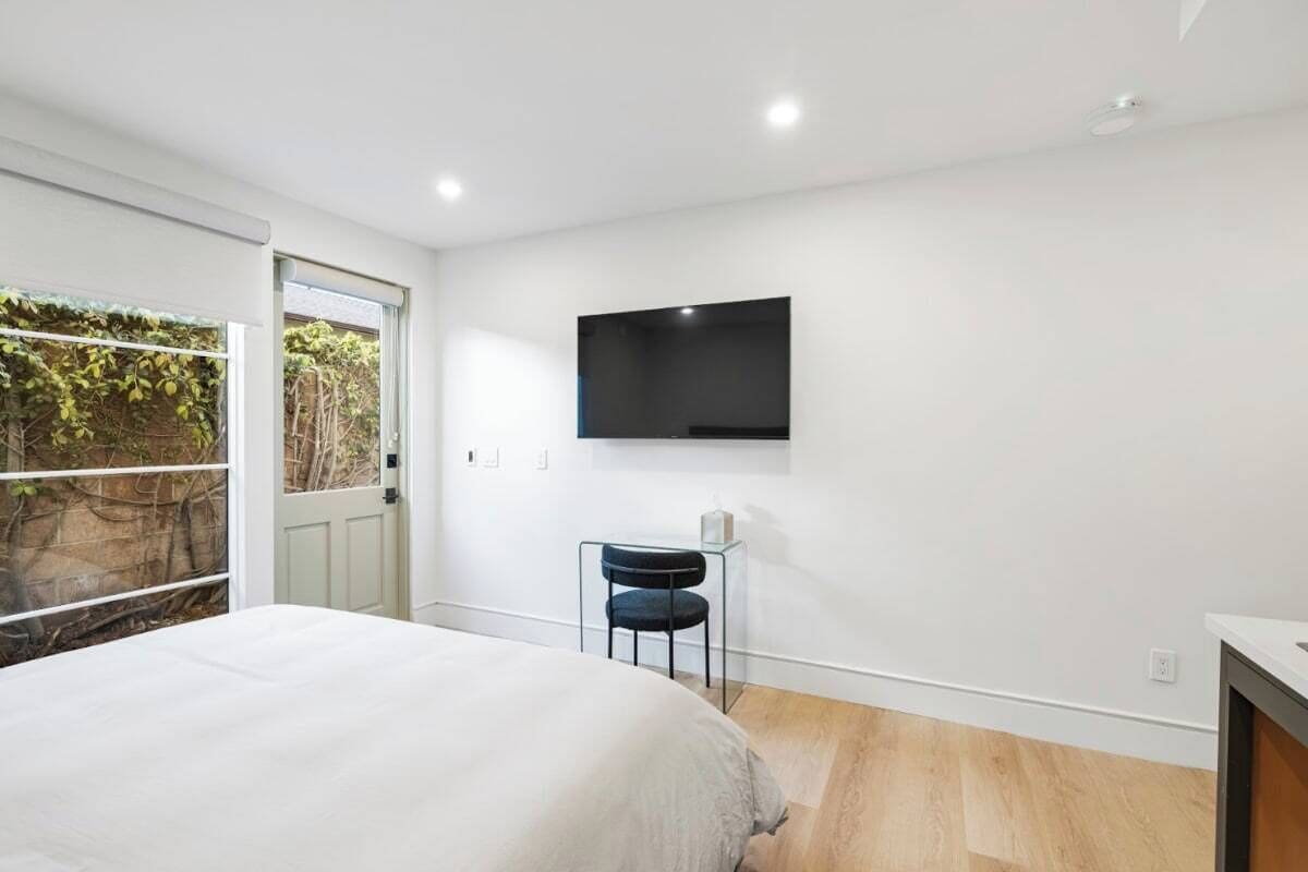 Un dormitorio con cama, televisor montado en la pared y una silla.