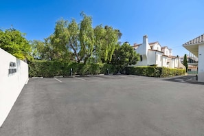 A parking lot with white buildings and trees in the background. - Casa Jardin, a ZenStay Hotel (Santa Barbara)