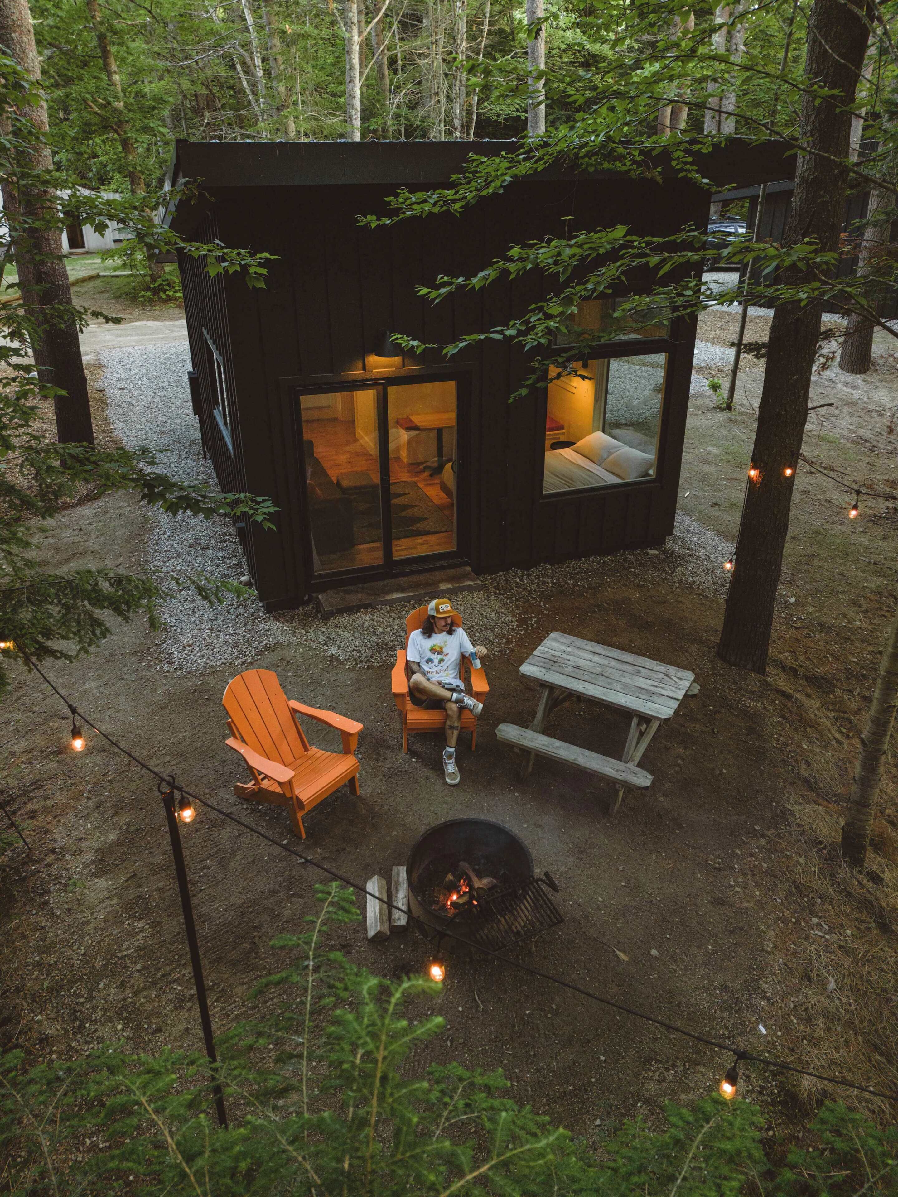 A cabin with a glass door entrance, a fire pit, and outdoor seating.