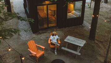 A cabin with a glass door entrance, a fire pit, and outdoor seating.