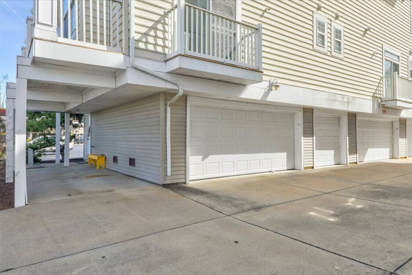A two-story building with a covered front porch, a balcony, and a garage with four doors.