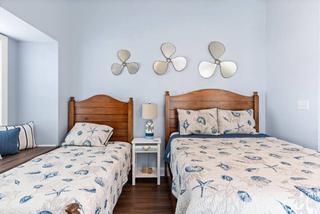 A bedroom with two wooden beds, matching headboards, and a nightstand with a lamp.
