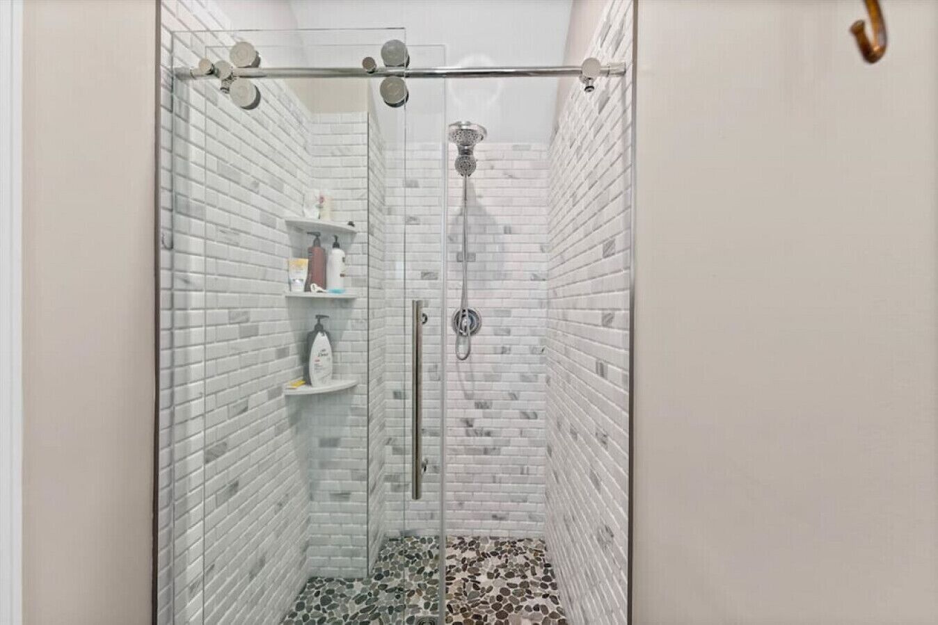 Une douche entièrementClose avec des murs recouverts de carreaux blancs et un sol en pierre.